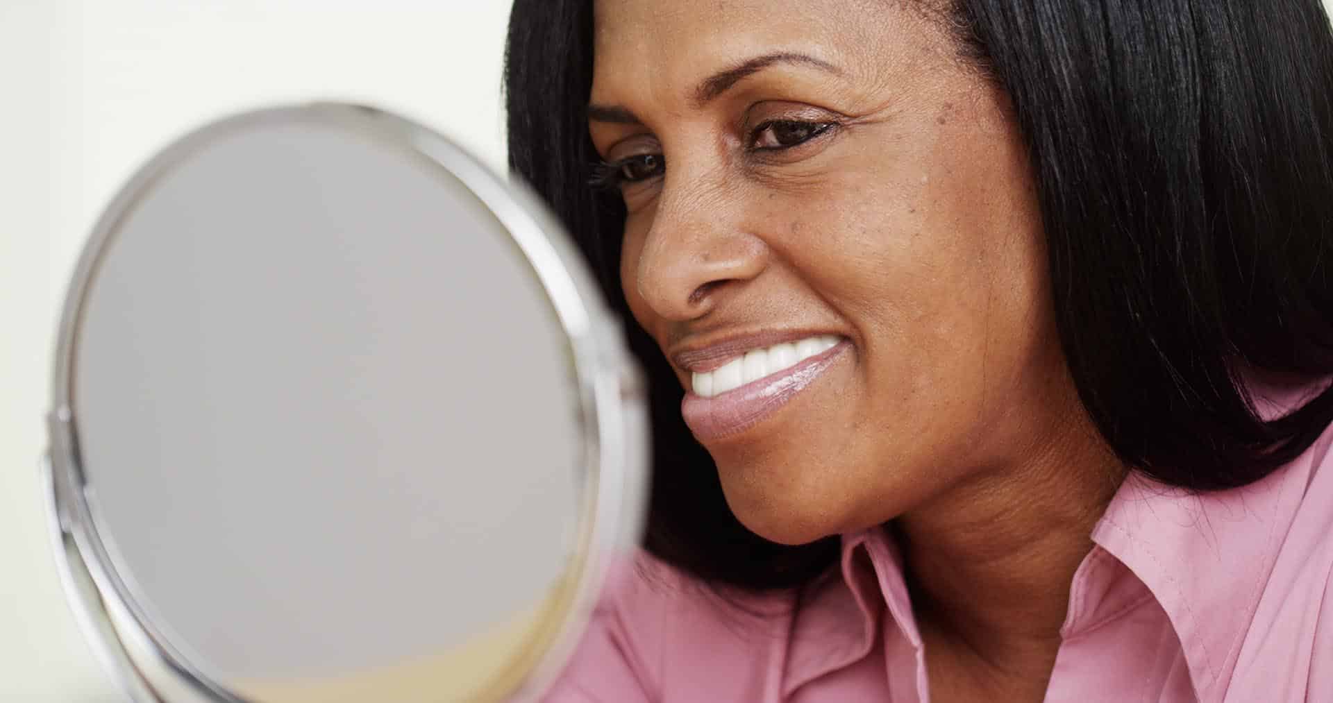 Woman admiring her new dentures in the mirror.
